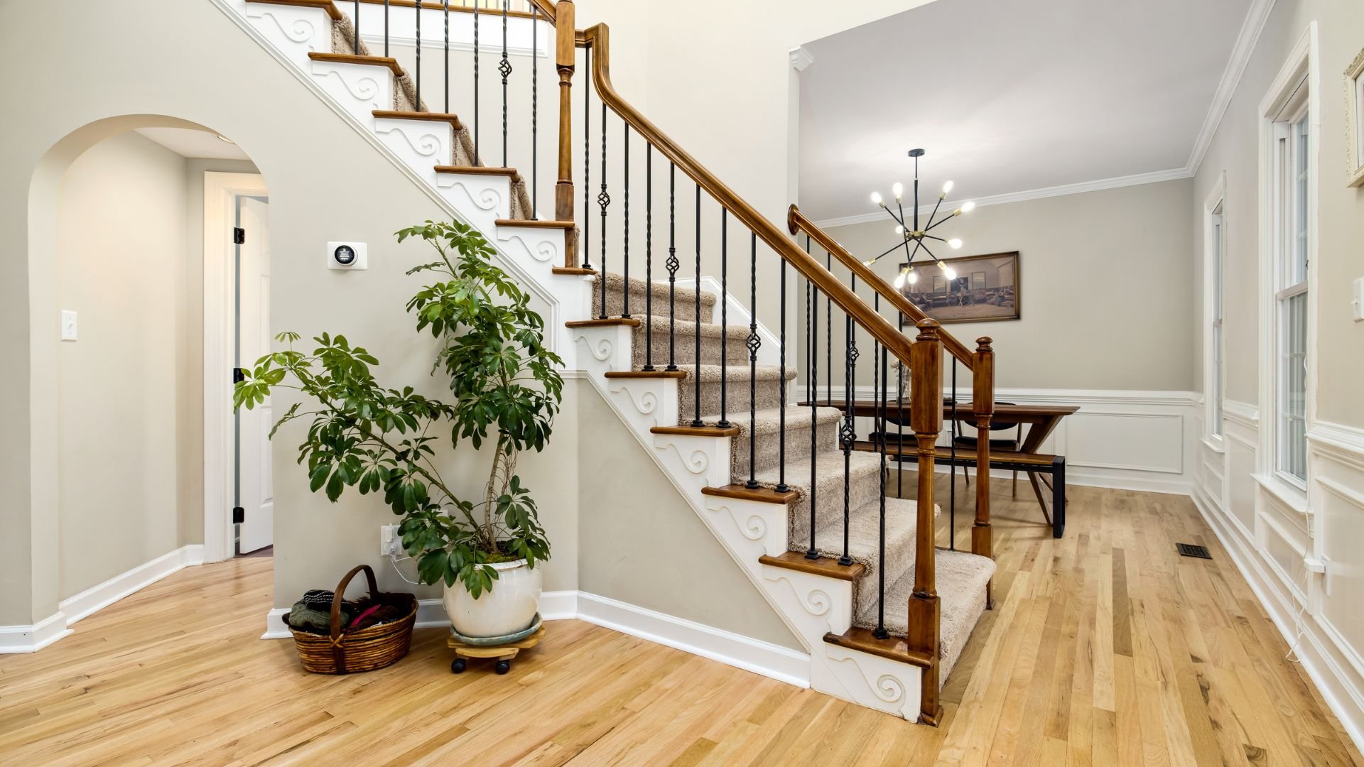 Elegant interior with wooden staircase, carpeted steps, and potted plant