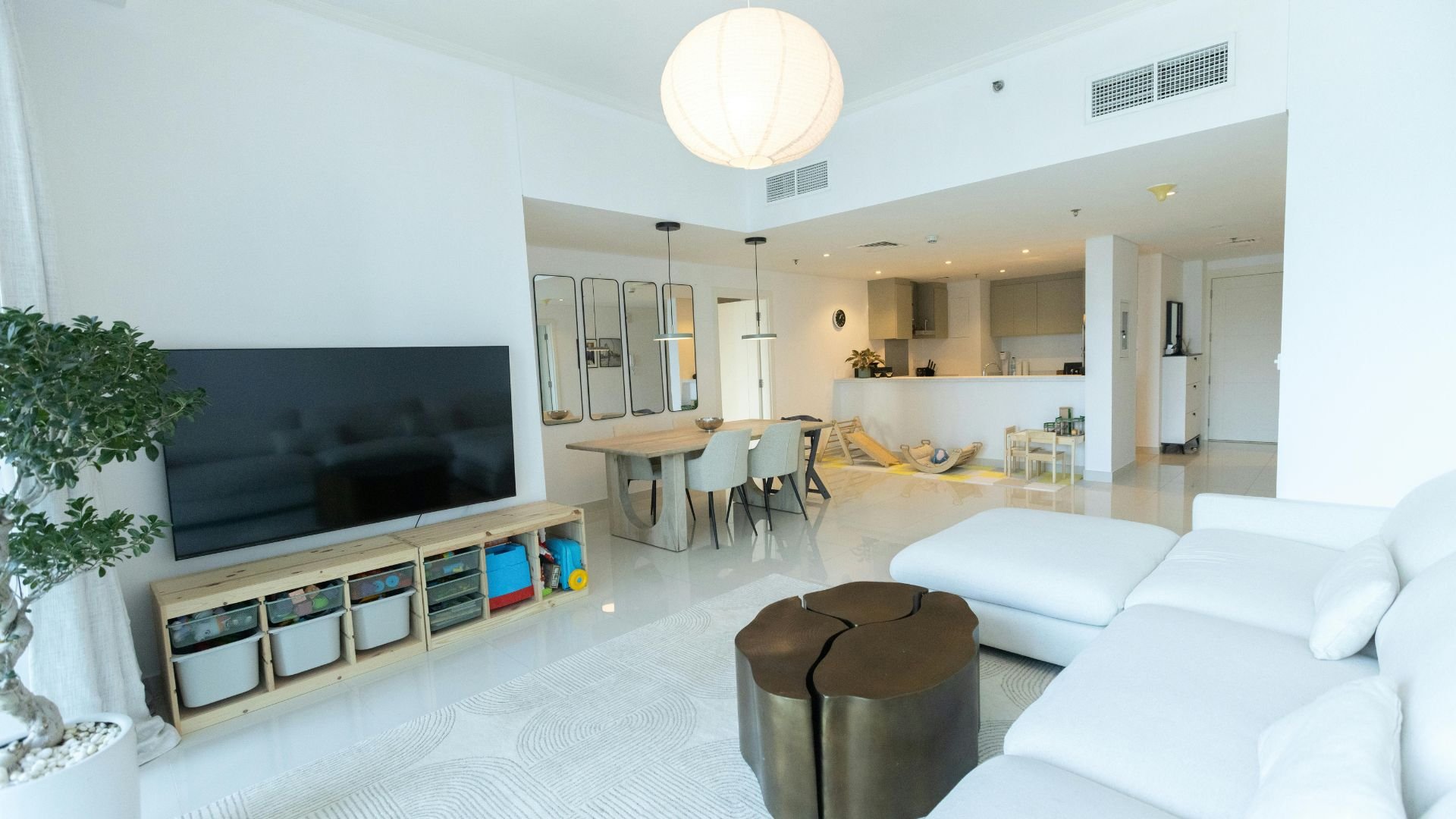 Modern, minimalist living space with white furniture, dining area, and storage